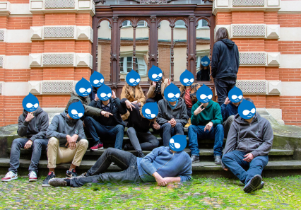 Photo de groupe dans la cour du bureau avec le logo Drupal sur le visage de chaque personne